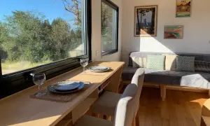 Intérieur d'une tiny house dans les Landes, avec un coin repas face à la nature et un canapé confortable.