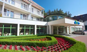 GeoVita Dąbki cennik: nowoczesny budynek hotelowy z zadbanym ogrodem i kwiatami.
