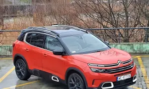 Pomarańczowy Citroen C5 Aircross z czarnym dachem stoi na mokrym parkingu.