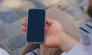 Mężczyzna trzyma iPhone 13 w przezroczystym etui. Chcesz wiedzieć, jak wyłączyć iPhone 13?