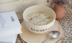 Misternie przygotowana owsianka na śniadanie, a obok książka. Czy płatki owsiane mają gluten? To pytanie nurtuje wielu.