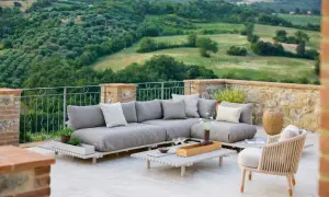 Eine stilvolle Dachterrasse gestalten: Gemütliche Lounge-Möbel mit Blick auf grüne Hügel laden zum Entspannen ein.