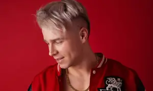 Młody mężczyzna z blond włosami i złotym łańcuchem na szyi, w czerwonej kurtce. Ile lat ma Skolim?