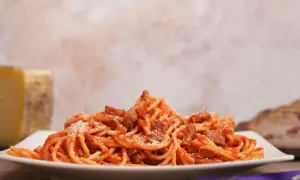 Un piatto di spaghetti conditi con sugo rosso e guanciale croccante, un assaggio dell'amatriciana ricetta originale di Amatrice.
