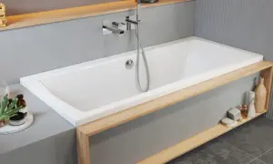 Moderne Badewanne einbauen: Weiße Wanne mit Holzakzenten, Armatur und Handbrause. Dekorative Elemente wie Lampen und Flaschen schmücken die Ablage.