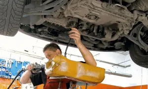 Mechanik wymienia olej w skrzyni biegów DSG, używając żółtego zbiornika i pompy.