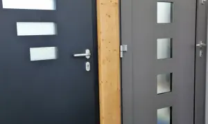 Dwie nowoczesne drzwi wejściowe, ciemnoszare i szare, z przeszkleniami. Dowiedz się, jak uszczelnić drzwi wejściowe, by zapewnić komfort.