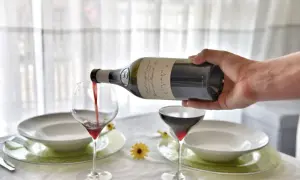 Versando vino rosso nel bicchiere, un gesto che anticipa una cena speciale.