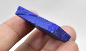 Królewski lapis lazuli, kamień o intensywnym niebieskim kolorze, trzymany w palcach.