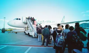 Ludzie wchodzą po schodach do samolotu. Pamiętaj, czego nie można brać na lotnisko, by podróż przebiegła gładko.