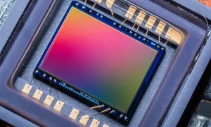Sensore di immagine 576 megapixel con sfumature arcobaleno, collegato da sottili fili dorati a contatti metallici.