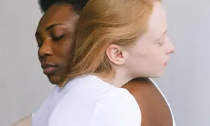 Twee vrouwen, één met donkere huid, de ander met lichte huid, omhelzen elkaar. Een beeld van verbinding, dat het verschil tussen compassie en empathie illustreert.