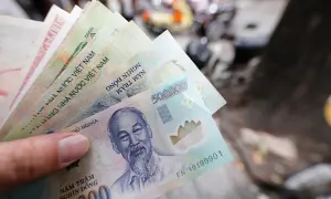 Dłoń trzyma stos banknotów, w tym 500 000 dongów, waluta w Hanoi.