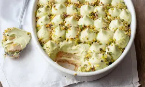 Un cremoso tiramisù al pistacchio, guarnito con granella di pistacchi, pronto per essere gustato.