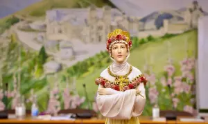 Figurka przedstawia postać z la salette objawienia, ubraną w białe szaty i złotą koronę z róż. Tło to malowidło górskiego krajobrazu.