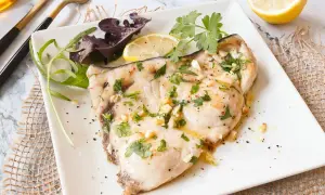 Delicioso emperador a la plancha con ajo, perejil y limón, servido con ensalada.
