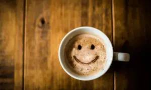 Tasse de café avec un visage souriant, une boisson qui ne fait pas grossir si consommée avec modération.