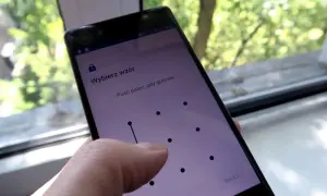 Telefon z ekranem blokady, gdzie wybierasz **wzór** 15 najpopularniejszych blokad. Palec rysuje linię na siatce kropek.