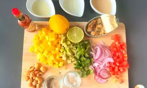 Mise en place para ceviche: mango, aguacate, cebolla morada, tomate, cilantro, limón, lima, mejillones en lata, maíz tostado, Tabasco y líquidos.