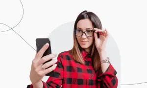 Kobieta w okularach i koszuli w kratę robi selfie, zastanawiając się, czy do Finlandii potrzebny jest paszport.