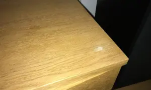 En träyta med tydlig ådring, kanske redo att slipa faner för en jämnare finish. En vit fläck syns på kanten.