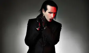Marilyn Manson zespół w czarnym garniturze, z czerwonym makijażem i rękawiczkami.
