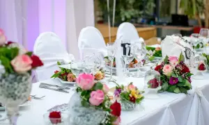 Elegancko nakryty stół weselny z bukietami róż i goździków. Idealne pomysły na wesele, pełne romantyzmu i stylu.