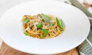 En krämig portion spaghetti alla nerano, toppad med färsk basilika och riven parmesan.