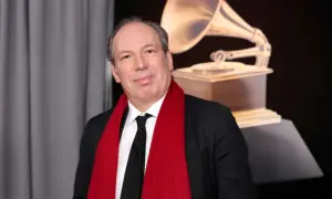 Hans Zimmer, który napisał muzykę do filmu Gladiator, pozuje z czerwoną szarfą i statuetką Grammy.