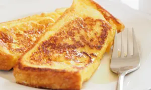 Goldbraune arme ritter, knusprig gebraten und mit Sirup beträufelt, warten auf eine Gabel.