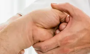 Arzt untersucht Hand, tastet den Os lunatum ab.