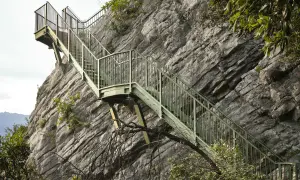 Scalinata metallica aggrappata alla roccia, un sentiero a Torbole che sfida la tempesta.