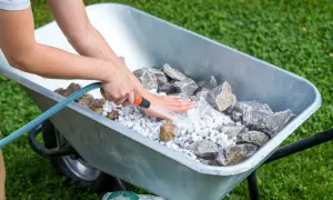 Beim **gartenbrunnen selber bauen** werden Steine in einer Schubkarre mit Wasser abgespült.