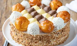 Una magnifica torta Saint Honoré, decorata con bignè caramellati, ciuffi di panna montata e crema pasticcera al cioccolato e vaniglia.