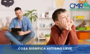 Bambino pensieroso in terapia, con un uomo sullo sfondo. Si parla di autismo lieve e della sua percentuale di invalidità.
