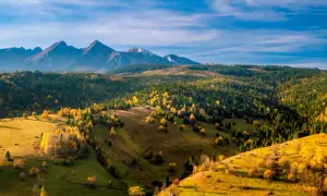 Jesienne słońce oświetla wzgórza i lasy, tworząc malowniczy krajobraz. Idealne tatry słowackie szlaki dla średnio zaawansowanych.