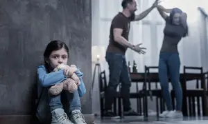 Przerażona dziewczynka tuli misia, podczas gdy rodzice kłócą się w tle. Czy to niebieska karta co to za sytuacja?