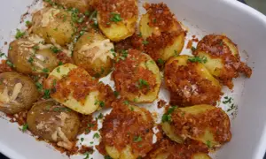 Knusprige parmesan kartoffeln mit Petersilie und grobem Salz bestreut, bereit zum Genießen.