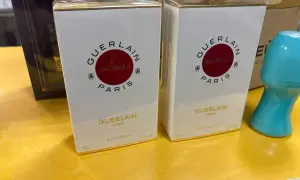 Dwie białe perfumy Samsara Guerlain 75 ml, każda w złotym opakowaniu, stoją na żółtej powierzchni.