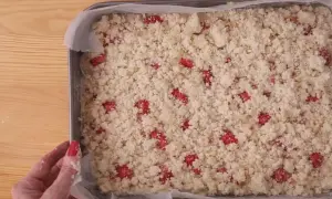 Gotowe do pieczenia ciasto ucierane z truskawkami, posypane kruszonką.