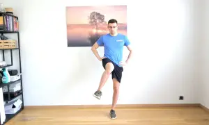 Homme effectuant un exercice de rotation interne hanche, jambe levée, mains sur les hanches.