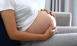 Kobieta w ciąży trzyma dłonie na brzuchu. Zastanawia się, jak przyspieszyć poród, czekając na dziecko.