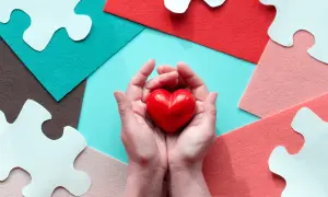 Mani che stringono un cuore rosso, circondate da pezzi di puzzle bianchi e sfondi colorati. Un gesto d'amore, perché si può fare una donazione tra fratelli.