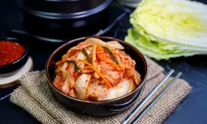 Miseczka z kimchi, pałeczki, miseczka z przyprawą i kapusta pekińska.