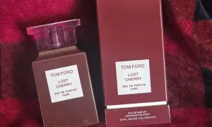 Elegancki flakon i pudełko perfum Tom Ford Lost Cherry 100 ml na tle czerwonego, miękkiego materiału.