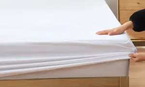 Dłonie naciągają białe prześcieradło na materac, pokazując, jak dopasowuje się ono do różnych rozmiarów prześcieradeł.