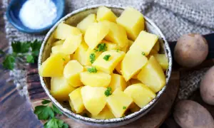 Schüssel mit dampfenden Salzkartoffeln, garniert mit Petersilie. Daneben eine kleine Schale Salz und rohe Kartoffeln.