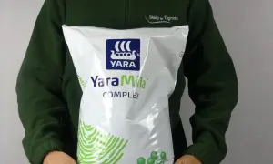 Osoba w zielonej bluzie trzyma worek nawozu YaraMila COMPLEX. Na opakowaniu widnieje logo YARA i informacja o wadze 10 kg.