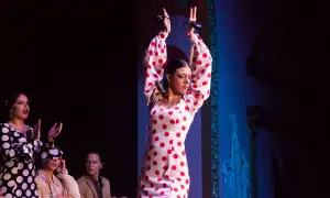 Mujer con vestido de lunares rojos y blancos, ejecutando un baile típico de Andalucía con castañuelas.