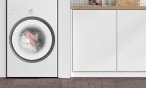 Lavatrice TCL in funzione, con panni colorati in movimento nel cestello. Il display indica 00:59, suggerendo quanto dura una lavatrice.